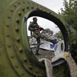 In this Sept. 9, 2014 file photo, a Pro-Russian rebel looks at pieces of the Malaysia Airlines Flight 17 plane near village of Rozsypne, eastern Ukraine. After a calamitous year for aviation, hundreds of government and industry officials will gather in Montreal this week in an attempt to reach a consensus on how to prevent any more airliners from disappearing without a trace or being shot down while flying over a conflict zone.