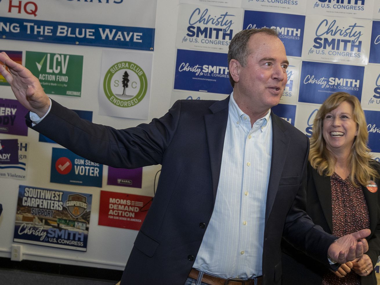 Congressman Adam Schiff and Christy Smith stand in front of a backdrop covered with logos.
