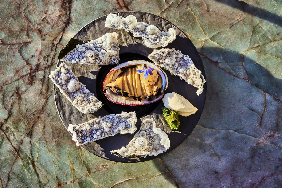 Baja abalone with rice paper nori crisps at Mother of Pearl in Downtown LA on a stone plate.
