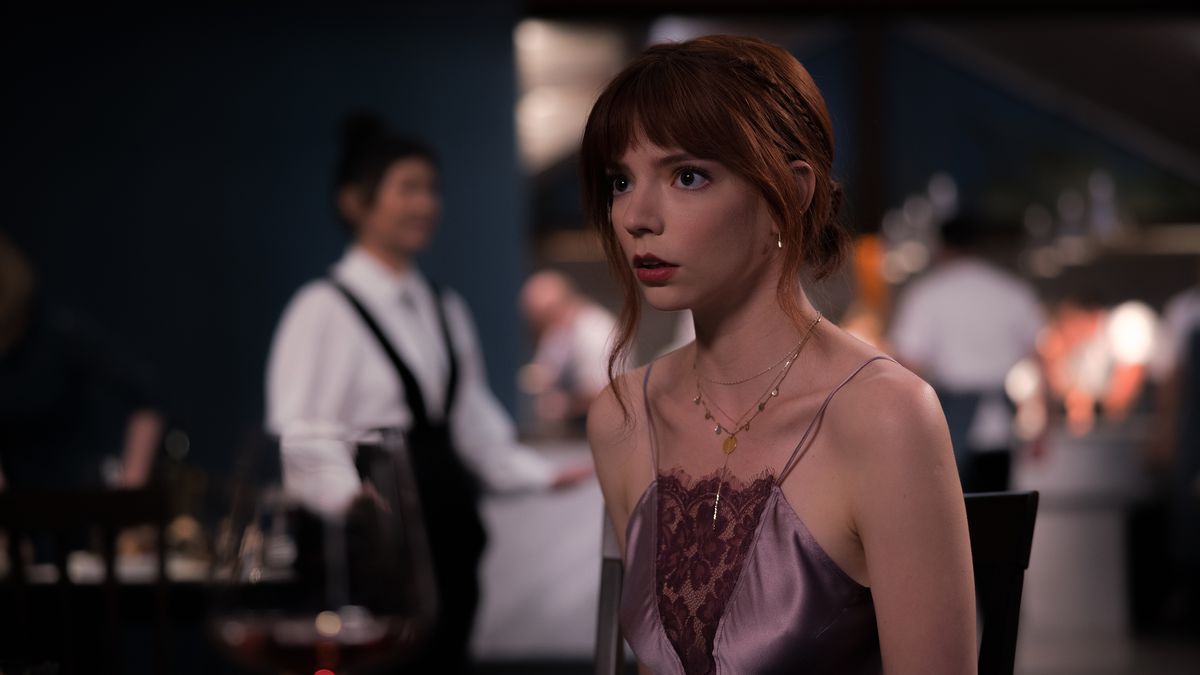 Margo (Anya Taylor-Joy), a young woman in a sheer spaghetti-strap dress, stares at something offscreen with a horrified expression in The Menu