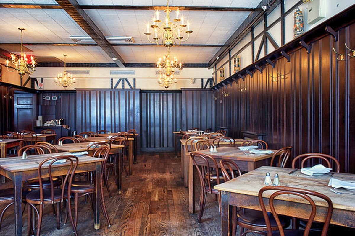 Peter Luger’s dining room with chandeliers and multiple tables set for service.