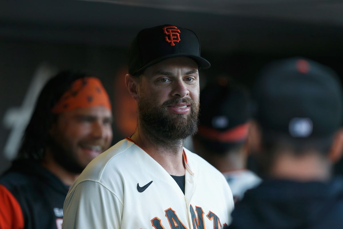 Brandon Belt smiling in the dugout with Brandon Crawford behind him