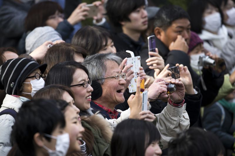 A crowd of people smile while taking photos. 