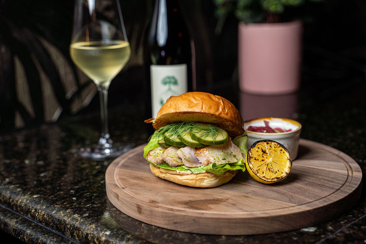 A fish sandwich and glass of wine.