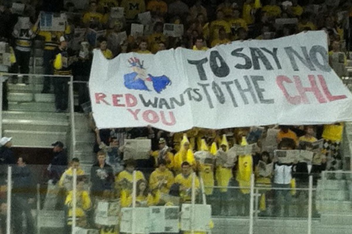 Michigan fans hold up a sign urging players to play NCAA instead of CHL.