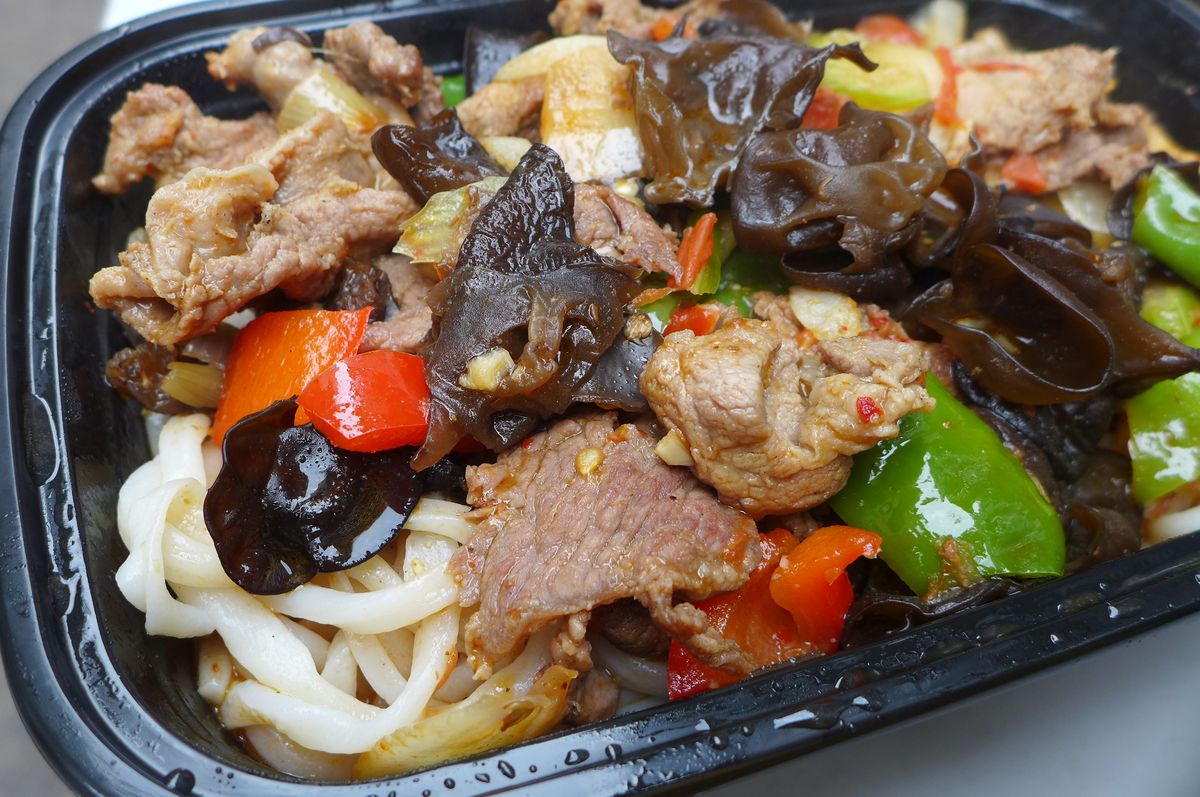A black plastic container with a chunky meat sauce and noodles peeping out underneath.