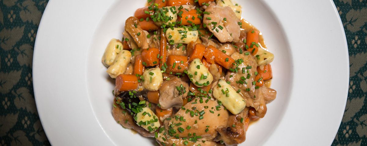 A bowl of Jewish stew with chicken and chives sprinkled on top.