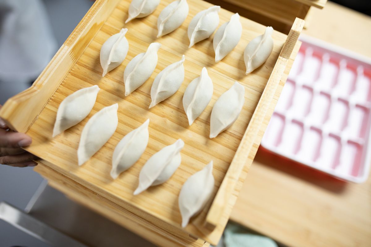 A wooden tray of uncooked dumplings. 