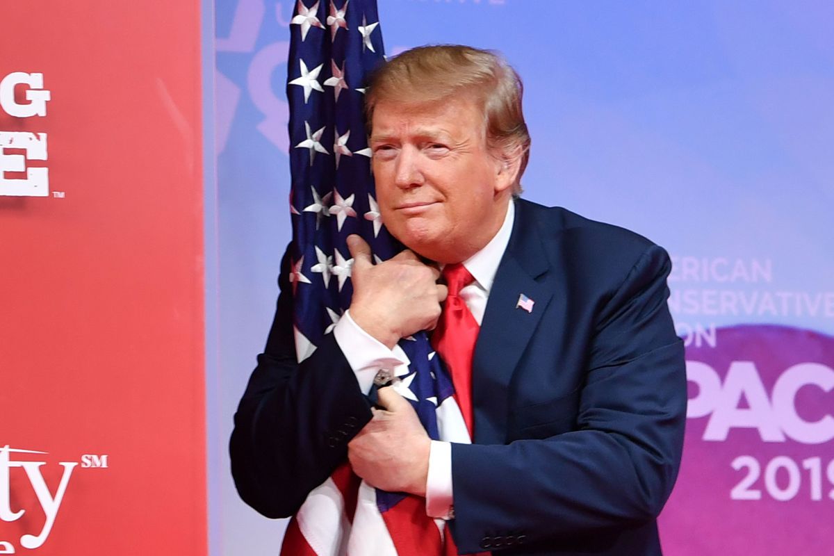 President Donald Trump hugs the US flag as he arrives to speak at the annual Conservative Political Action Conference (CPAC) in National Harbor, Maryland, on March 2, 2019.