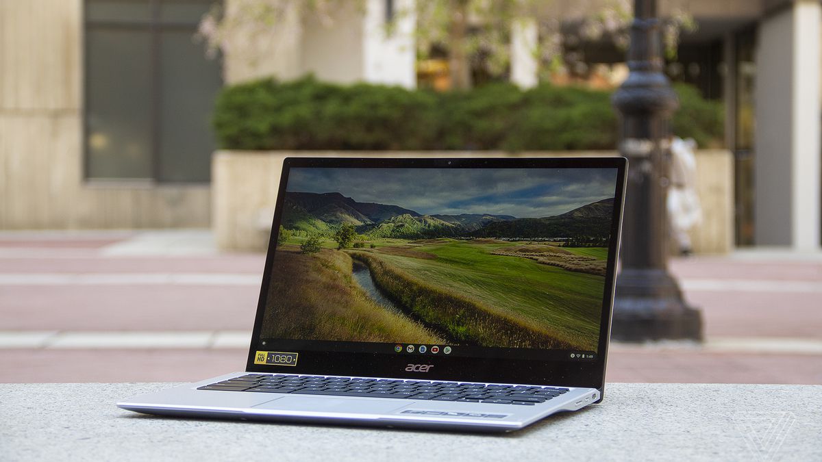 The Acer Chromebook Spin 513 sits on a stone bench, open, angled to the left. The screen displays a pastoral scene.