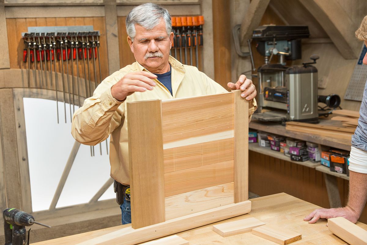 Man Slides Remaining Panel pieces Into Rails’ Dadoes Of Cedar Planter Box