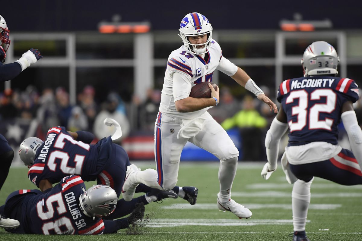 Buffalo Bills quarterback Josh Allen (17) runs with the ball while evading tackles by New England Patriots cornerback J.C. Jackson (27) and inside linebacker Jamie Collins (58) during the second half at Gillette Stadium.
