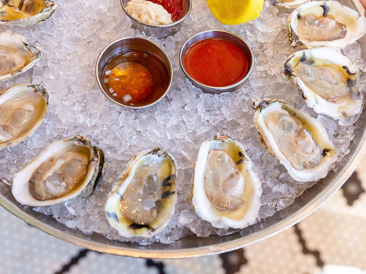 A platter of one dozen oysters on the half shelf over crushed ice with mignonette, horseradish sauce, and two lemon slices at the Select in Sandy Springs, GA.