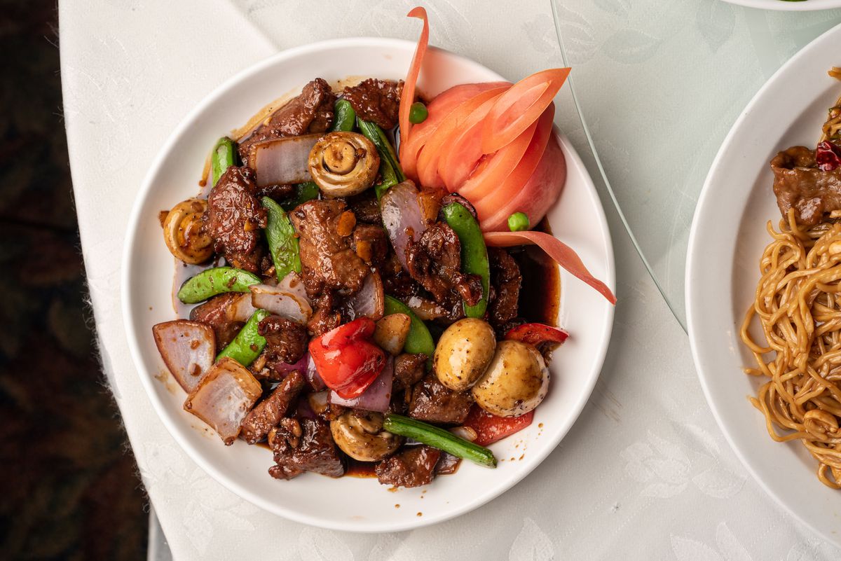 A plate filled with cubed steak, snap peas, mushrooms, and onions.
