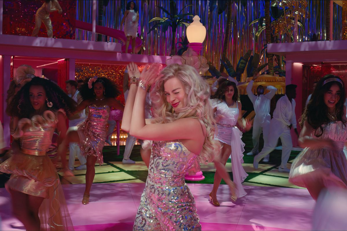 Robbie is mid-clap during a dance number at a big party at the Barbie Dreamhouse, surrounded by other guests in party outfits.