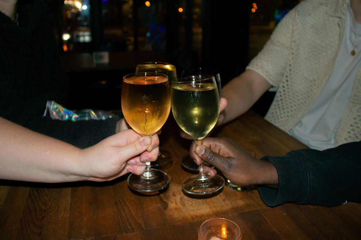 A group of people cheers wine glasses together.