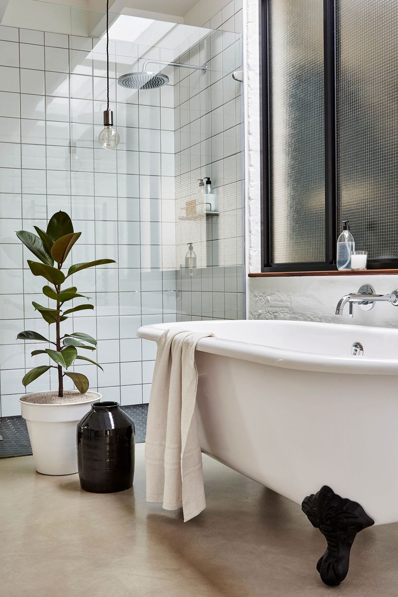 A bathroom with a clawfoot tub and a glass shower, also has a concrete floor. 