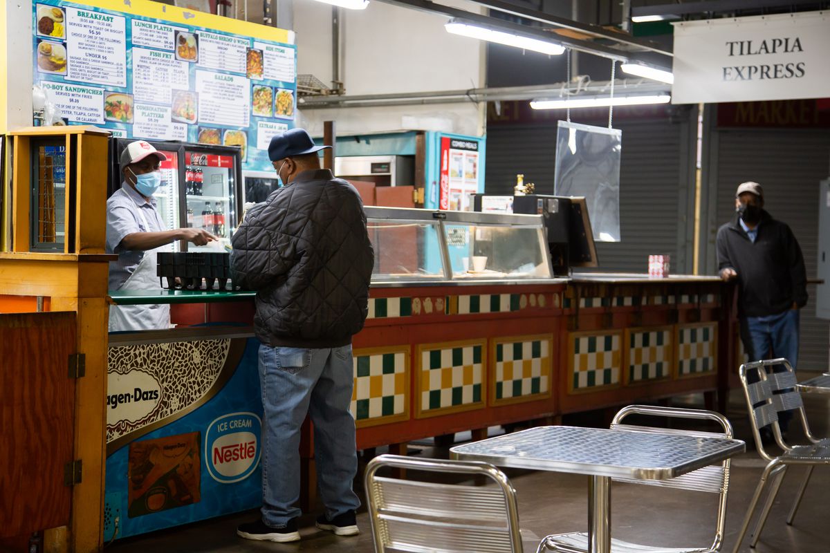 Δύο άτομα περιμένουν στην ουρά για εξυπηρέτηση στον πάγκο του εστιατορίου με θαλασσινά Tilapia Express μέσα στη Δημοτική Αγορά της Ατλάντα, στην αγορά Sweet Auburn Curb.