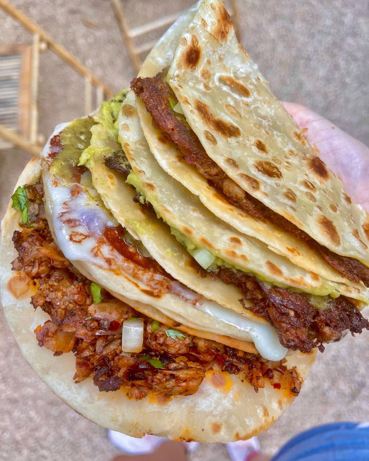 A handg holding up four tacos.