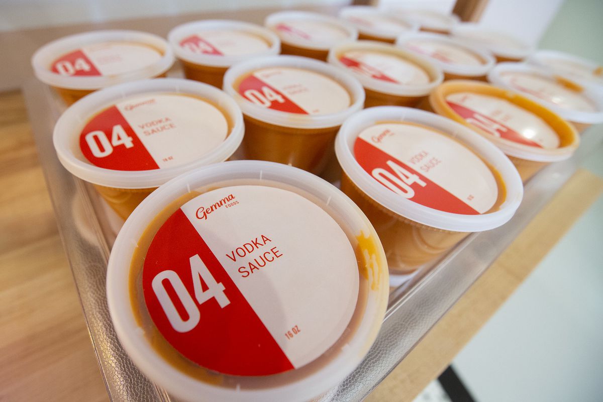 A bin of plastic containers labeled “vodka sauce” on the lid.