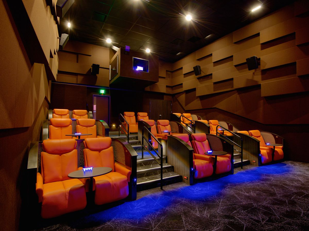 A wide shot of three rows of orange recliner two-seater pods at ipic theatre in Atlanta