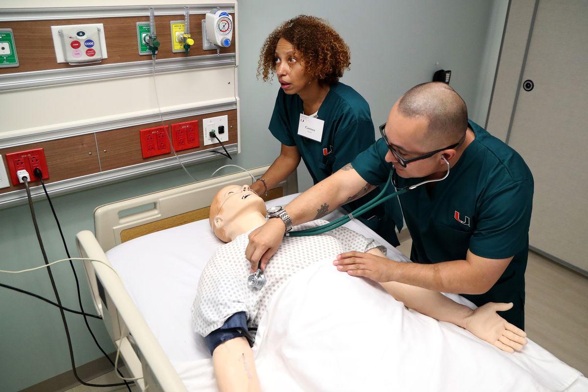 Two nurses treat a dummy patient on a gurney during a training simulation.