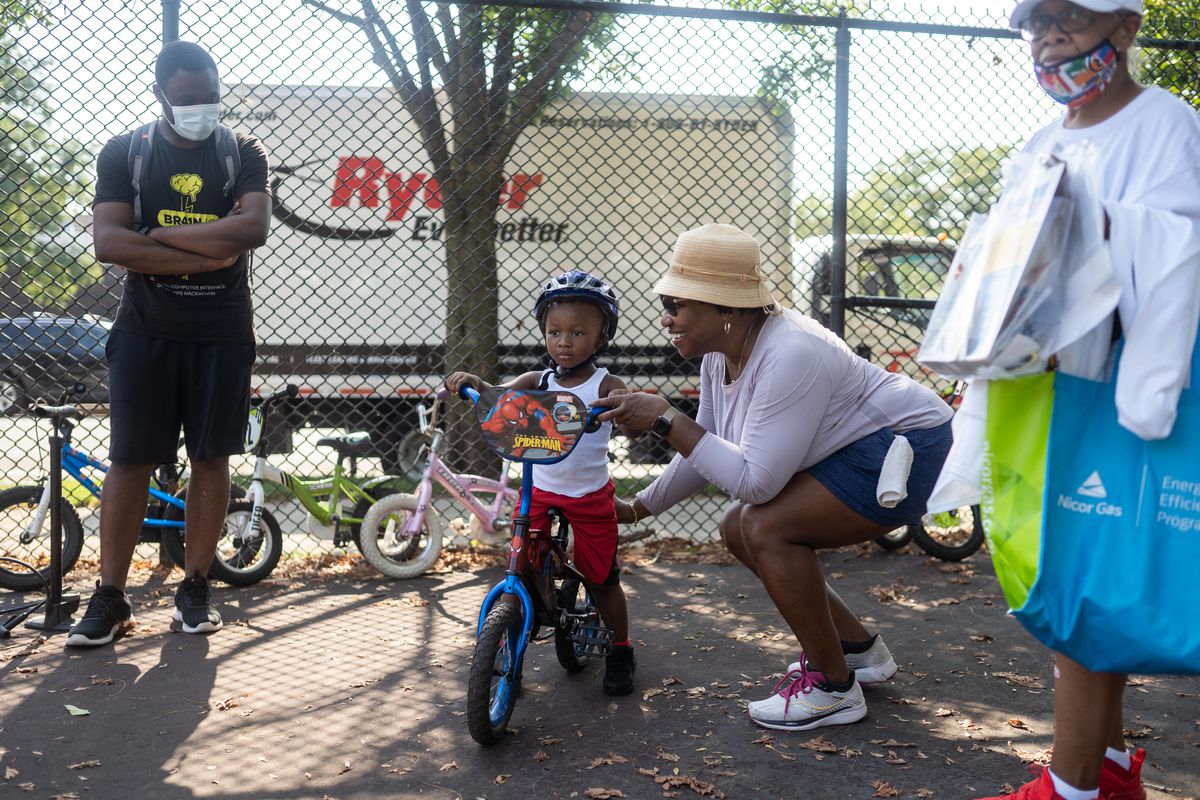 Darlena Burnett teaches Narsir Arnold to ride a bike during a bike giveaway and bicycle safety camp event at Union Park Saturday morning, Aug. 8, 2021.