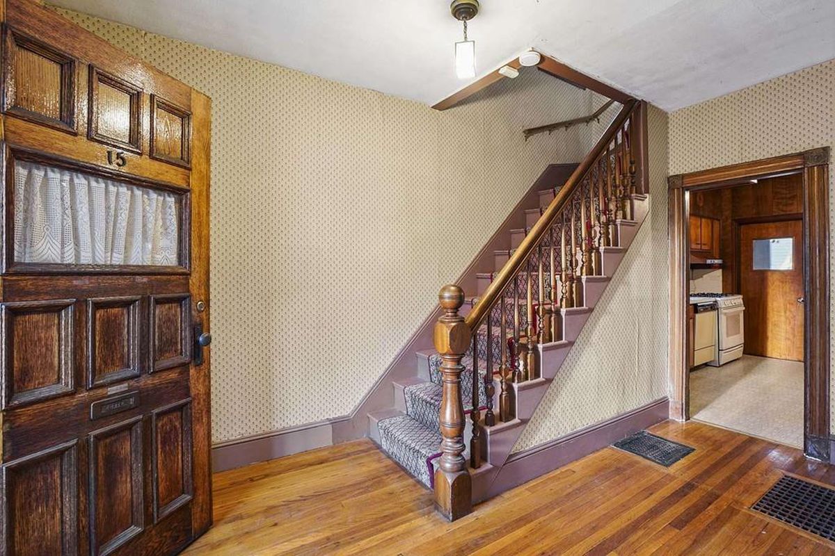 An old and in need of work entry foyer for a house, with a staircase leading up from it.