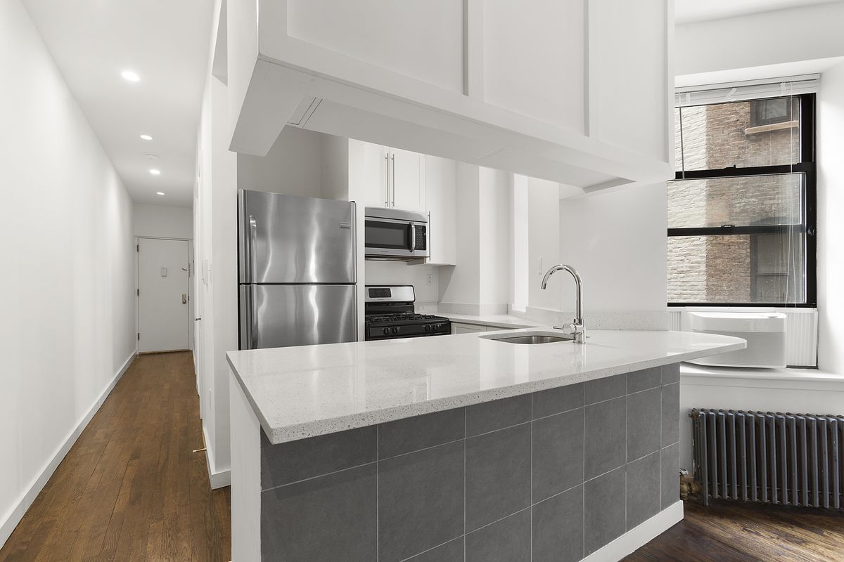 A kitchen with an island and white cabinetry. 