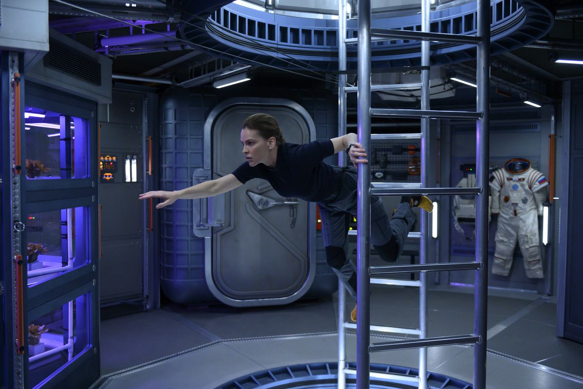 Hilary Swank clings to a ladder in zero gravity in the Netflix series Away