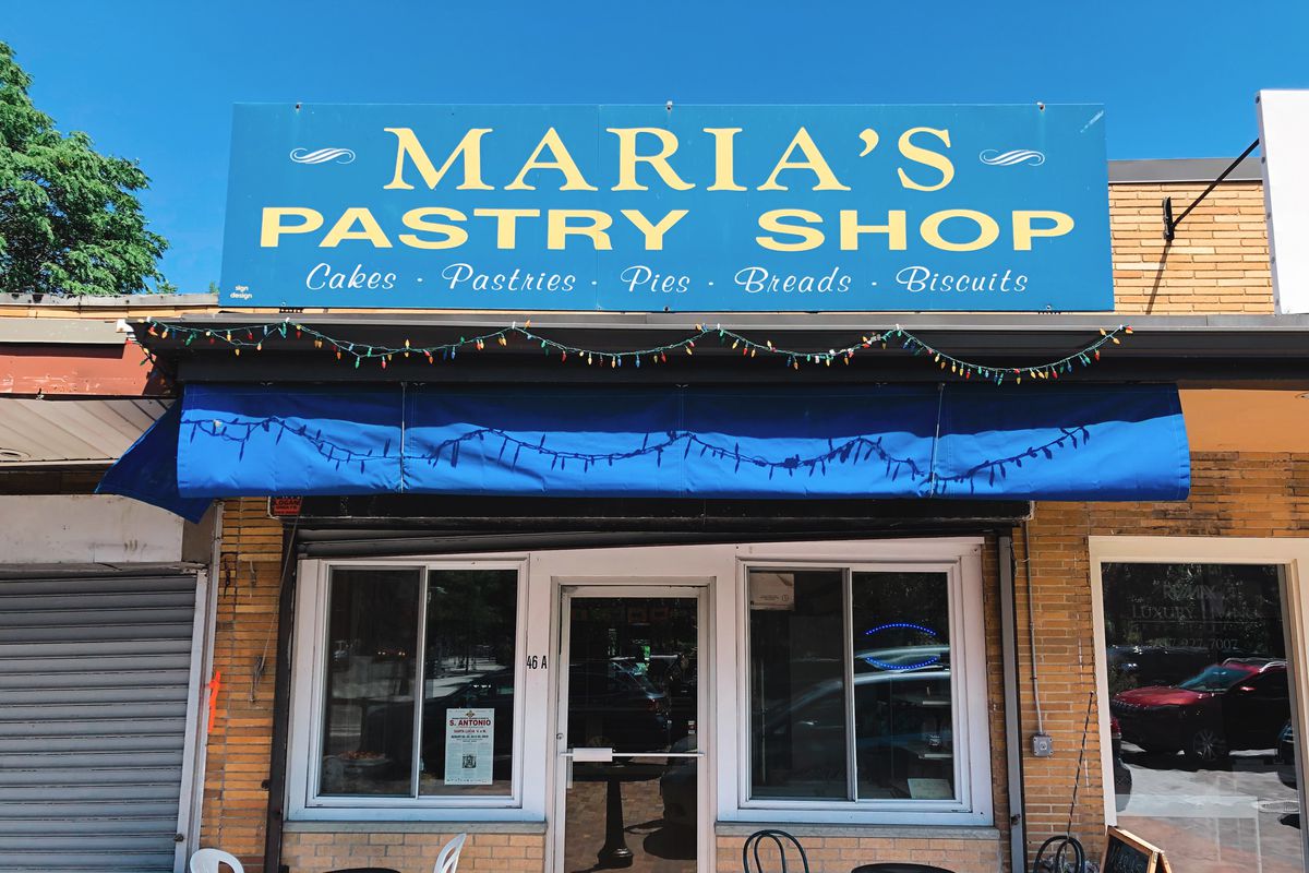 The blue awning of Maria’s Pastry Shop is lit brightly on a sunny day in Boston’s North End