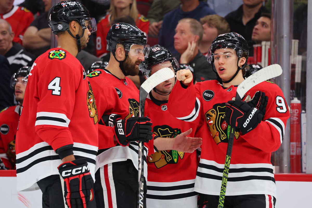 Connor Bedard #98 of the Chicago Blackhawks talks with Seth Jones #4, Nick Foligno #17 and Tyler Johnson #90 against the Boston Bruins during the second period at the United Center on October 24, 2023 in Chicago, Illinois.
