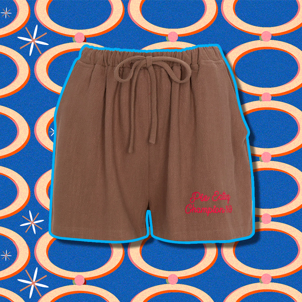 A pair of brown shorts with red embroidery reading “Pie Eating Champion”