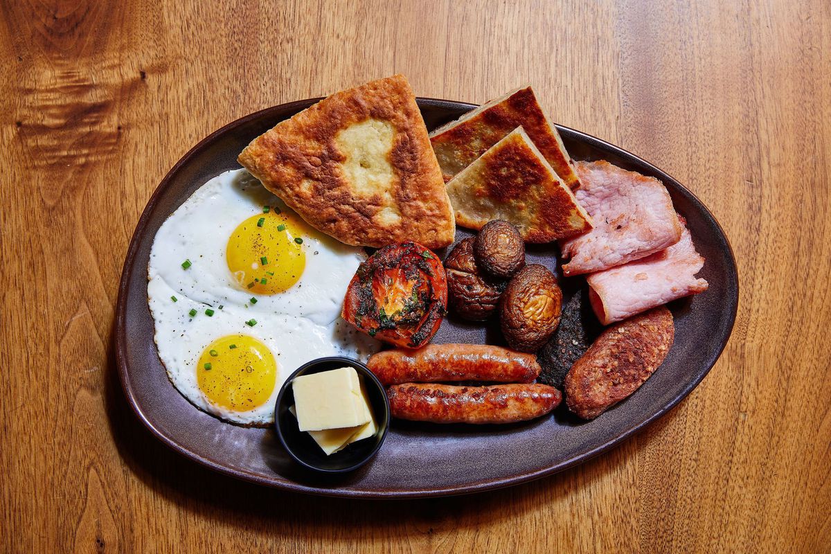 A plate of fried eggs, sausages, meats, and potatoes.