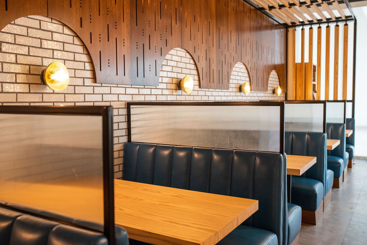 Blue leather booths line the neutral colored brick wall at the Usual in Atlanta, GA. 