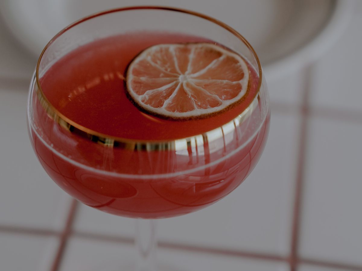 A cocktail with rum, juice, spices, and a lime slice.