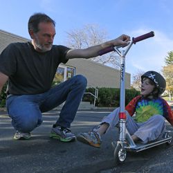 Jon Owen assists his son Ben with a scooter near their home on Thursday, Oct. 30, 2014, in Salt Lake City. Ben was diagnosed with autism spectrum disorder at age 2. Jon is president of the Utah Autism Coalition.