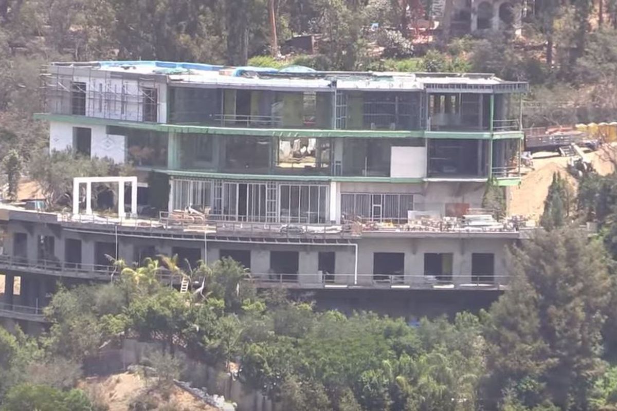 An aerial photo of a half-finished mansion jutting out of a hillside.