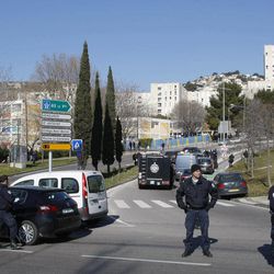 Police officers block the entrance of the Castellane housing project of Marseille, southern France, Monday, Feb.9, 2015. Police say gunmen have fired automatic weapons at the edge of a housing project the same day as the prime minister planned to visit the city. The project is rife with drug gangs and violence. No injuries were immediately reported. 