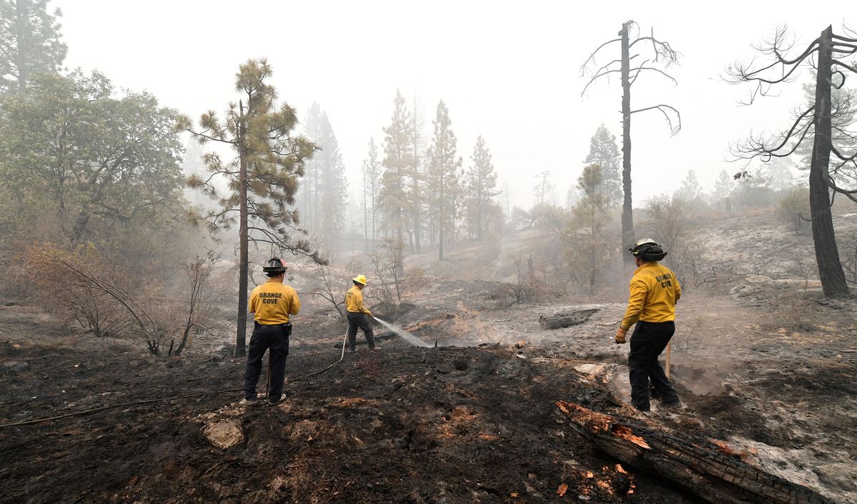 Firefighters put out burning embers in the Fresno County community of Bald Mountain, in the foothills of the Sierra Nevada mountains, on September 11, 2020