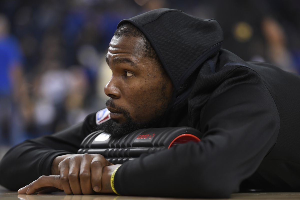 Golden State Warriors’ Kevin Durant (35) lays on the floor while being stretched by a trainer before playing the Brooklyn Nets during their NBA game at the Oracle Arena in Oakland, Calif. on Saturday, Nov. 10, 2018. (Jose Carlos Fajardo/Bay Area News Grou