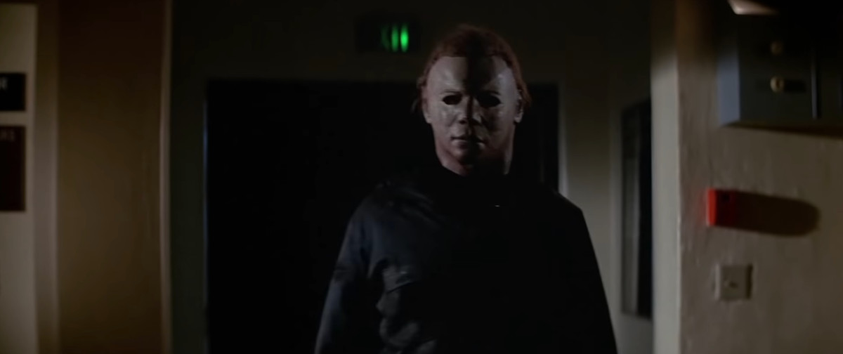 Michael Myers in his old-school mask, but now with redder hair, walks toward the camera menacingly in Halloween II