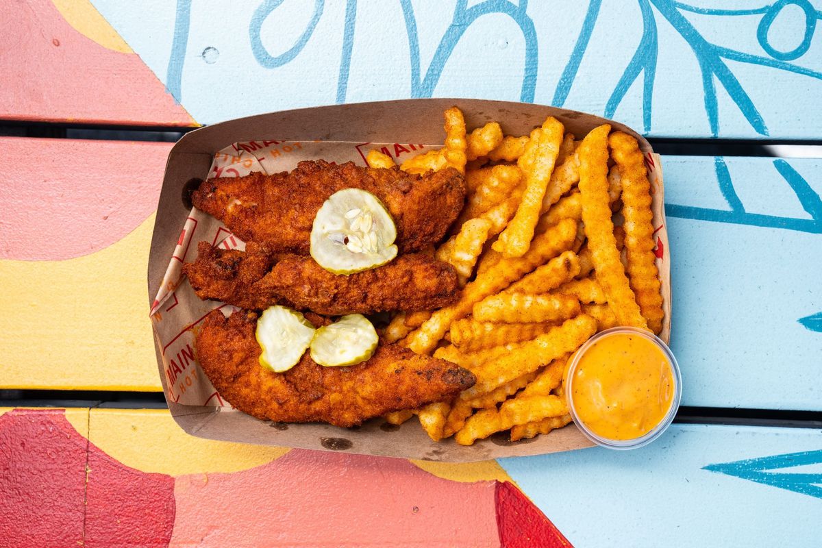 Hot chicken tenders with crinkle cut fries in a paper boat.