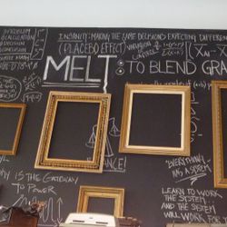 Black wall covered in chalk sayings. Kids can grab chalk and add to the wall.