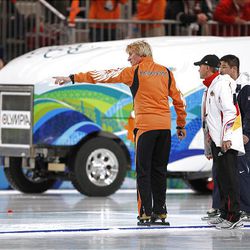 Coaches react as an ice preparation machine passes during a break in the the first of two heats of the men's 500 meter race at the Richmond Olympic Oval.