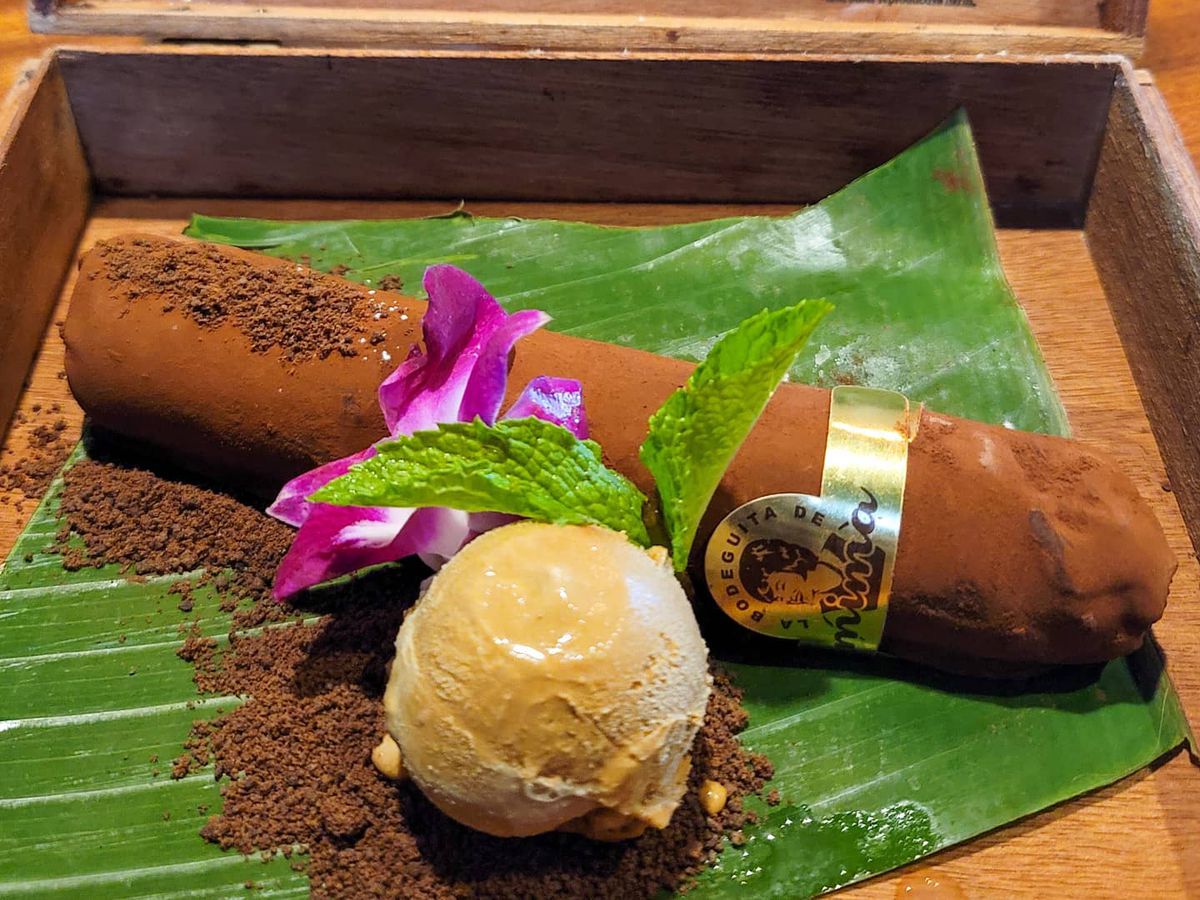 A chocolate cigar served in a cigar box with a mound of ice cream