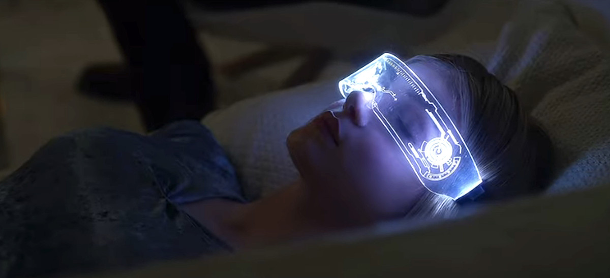 Elena Kampouris lies in bed wearing glowing AR goggles in Wifelike