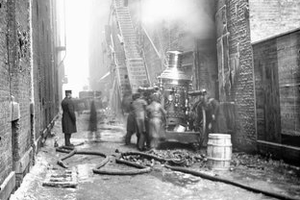 An alley behind the Iroquois Theater where firefighters fight a blaze in the theater