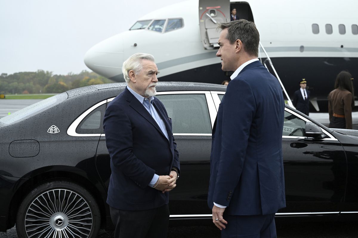 Logan Roy and Tom Wambsgams talk in front of a black car parked in front of a waiting private jet in the fourth season of HBO’s Succession.
