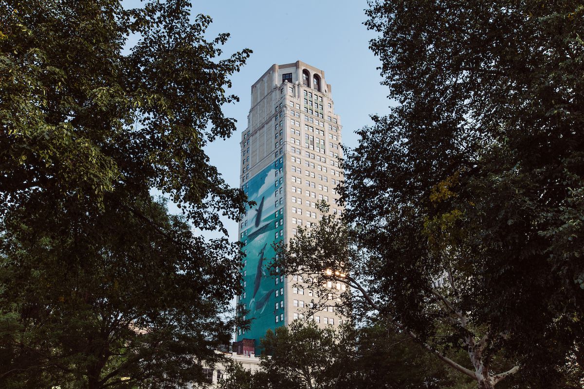 A tall building with a blue mural depicting whales on the side of it. 